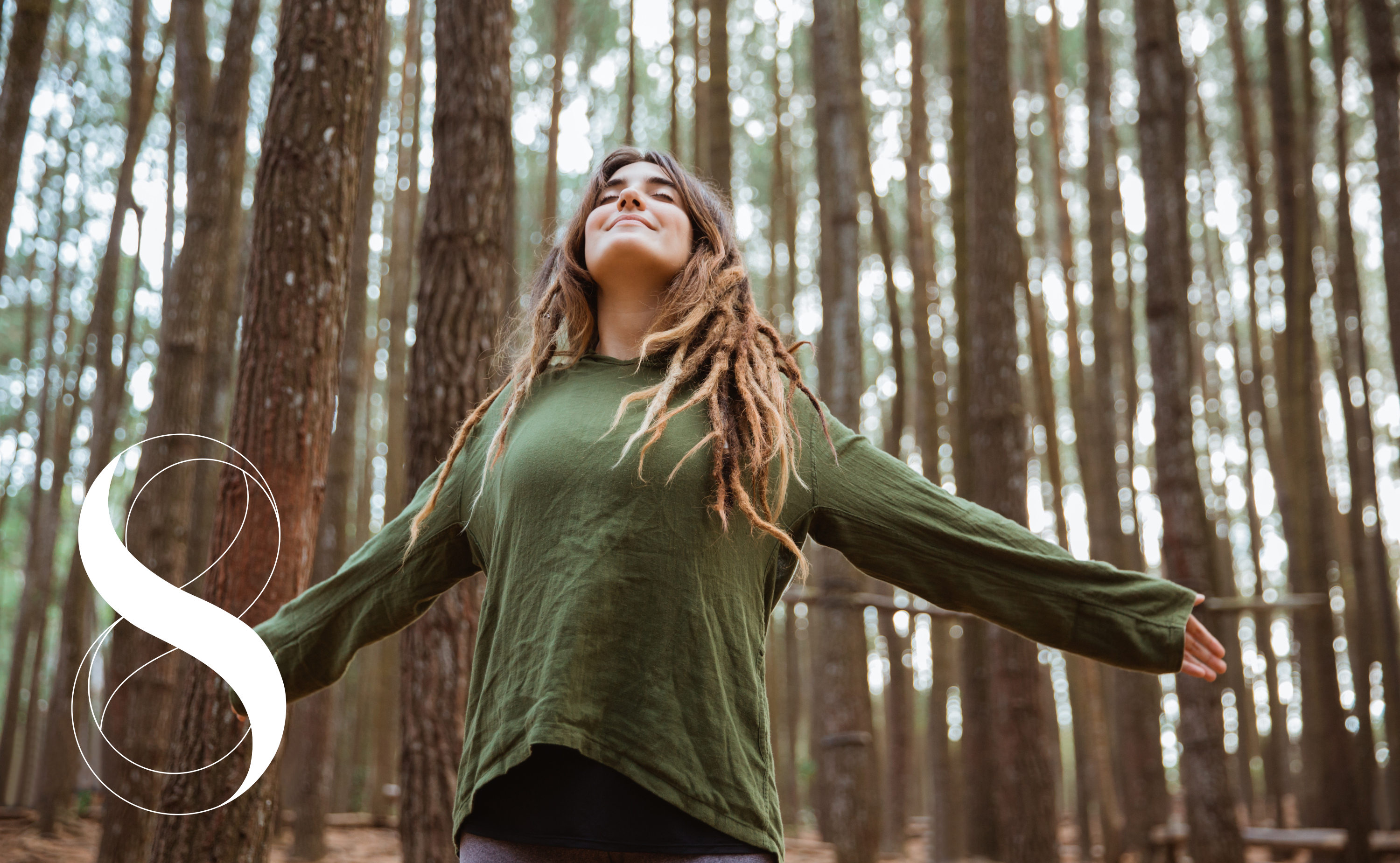 Junge Frau mit Dreadlocks, die mit geschlossenen Augen und ausgebreiteten Armen in einem Wald steht und tief durchatmet. Symbolfoto für die Fähigkeit, mit einer gesunden Lunge frei zu atmen.