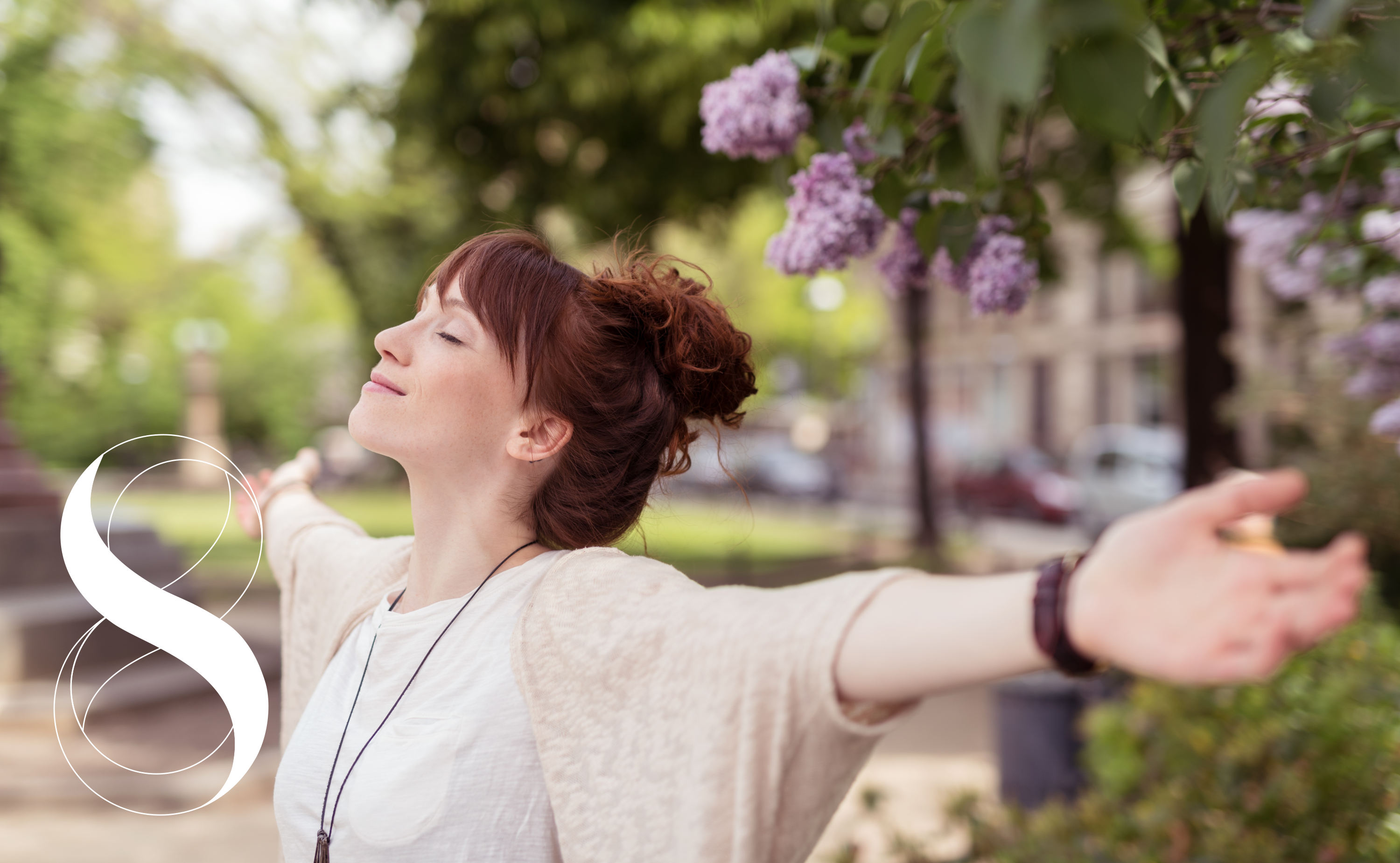 Eine Frau im Park streckt mit geschlossenen Augen die Arme auseinander, weil sie frei durchatmen kann. Sie steht symbolisch für Gesundheit durch natürliche Mittel gegen Allergien.